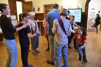 Menschen stehen im Kreis und spielen ein altes Bewegungsspiel