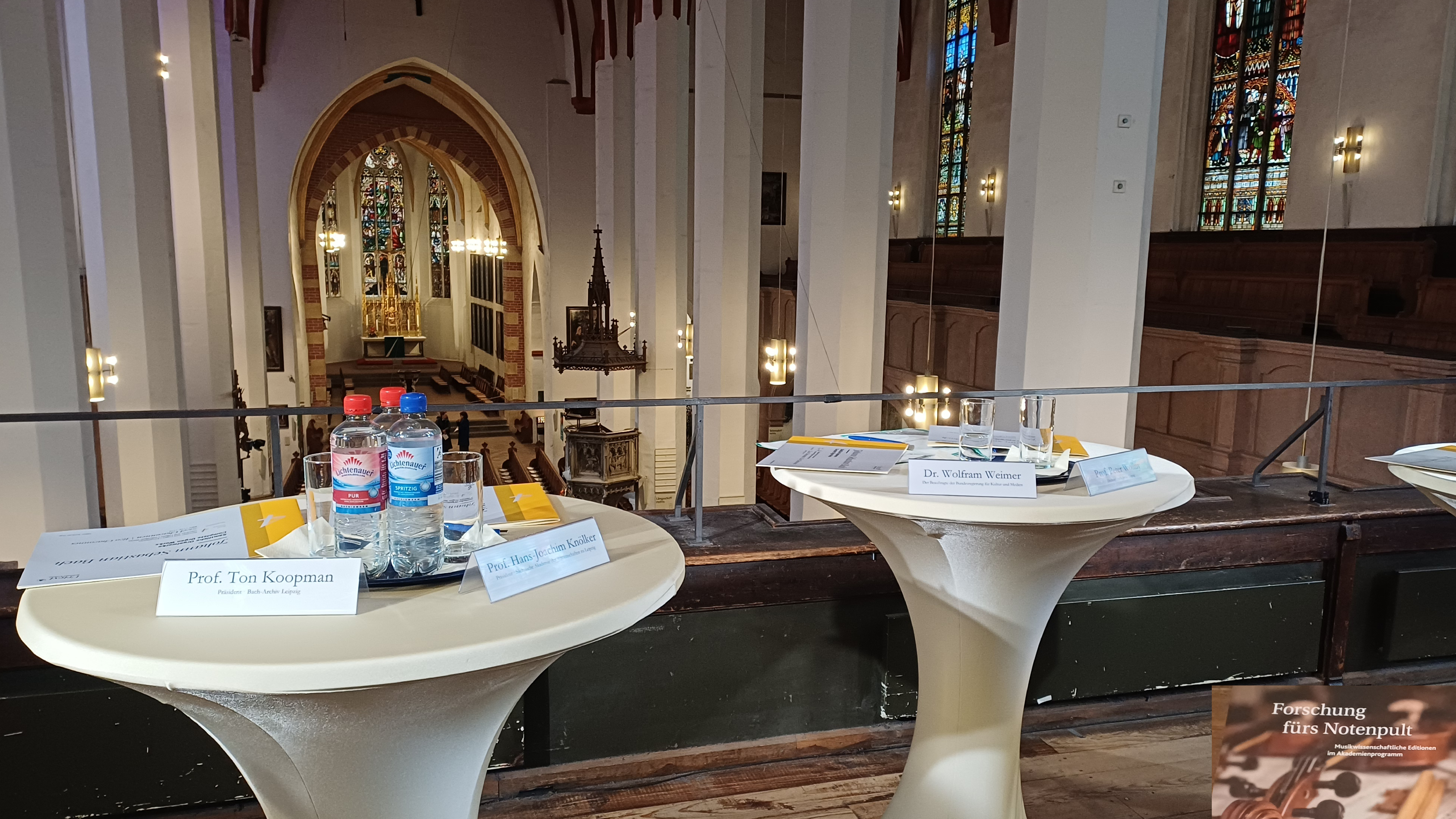 Zwei leere Stehtische in de Thomaskirche, auf denen Wasserflaschen und Namensschilder stehen.