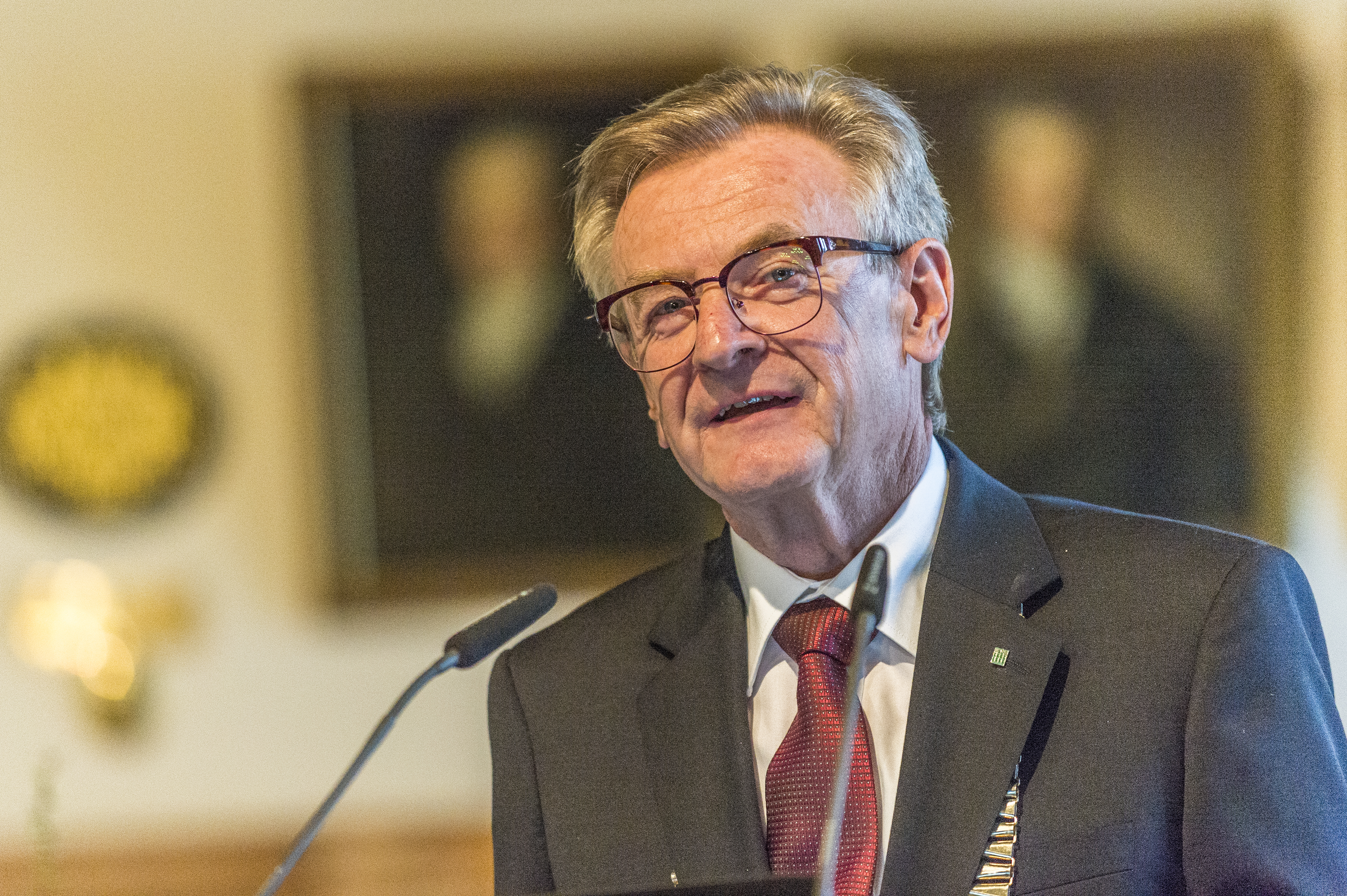 Eine männliche Person mit Brille steht an einem Rednerpult und spricht in ein Mikrofon.